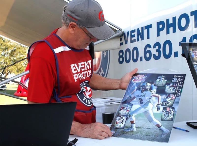 Crew member reviewing a printed action poster at the event photo stand