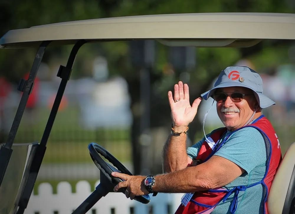 Glossy Finish crew member waving from a golf cart at a tournament