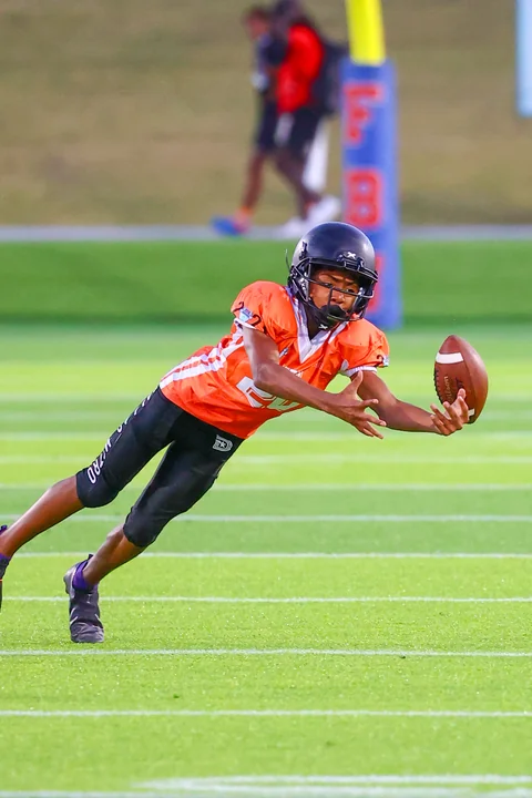 Receiver in orange diving for a one-handed catch