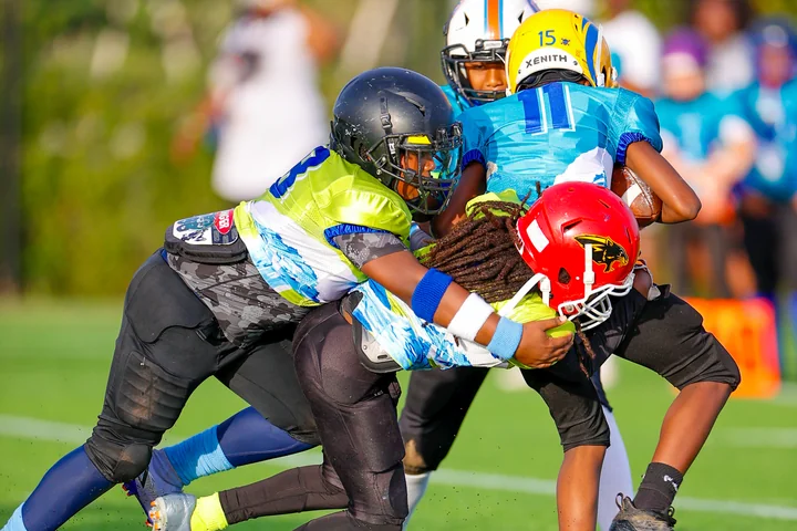 Defender in green wrapping up the ball carrier
