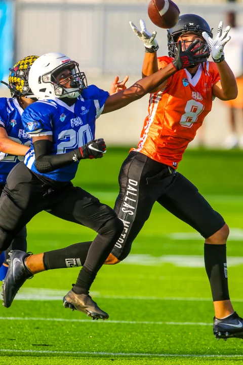 Receiver in orange reaching for a pass over a defender