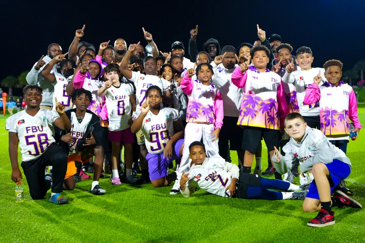 Team celebrating on the field at night, fingers raised