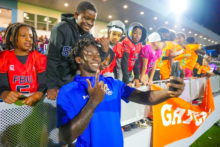 Guest posing for a selfie with young fans along the rail