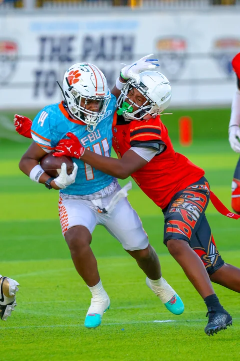 Defender in orange tackling a runner in light blue
