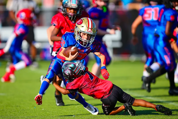 Runner in blue tackled by a defender in red