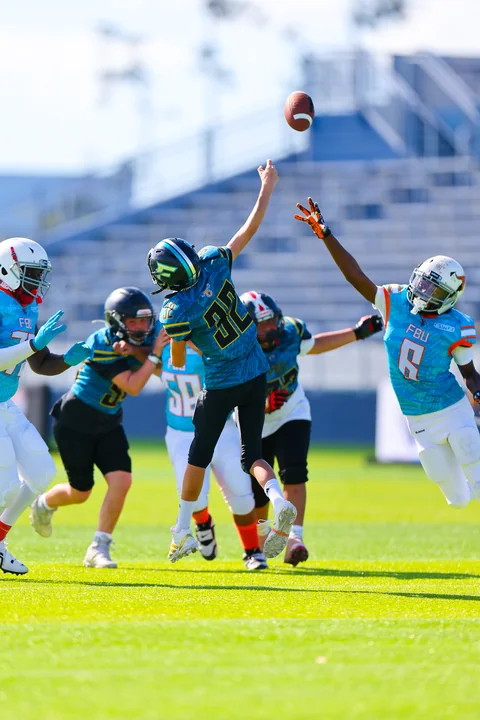 Quarterback throwing over a leaping defender