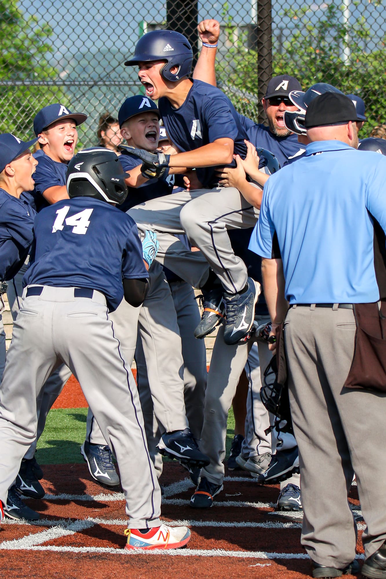 Youth baseball team celebrating together at home plate