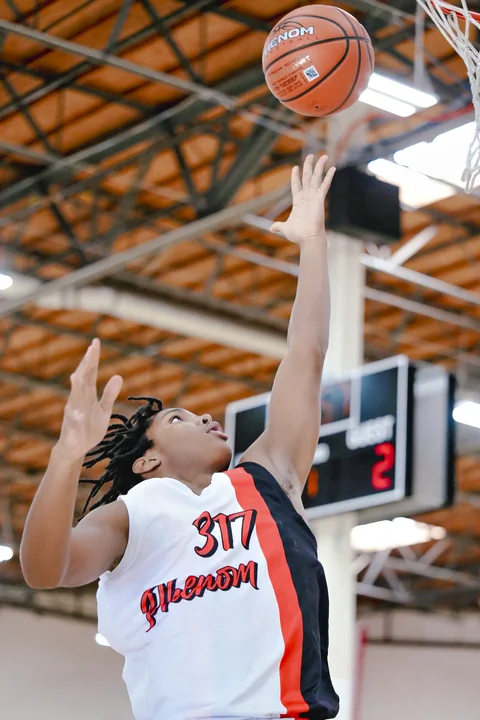 Player in white reaching to tip in a rebound