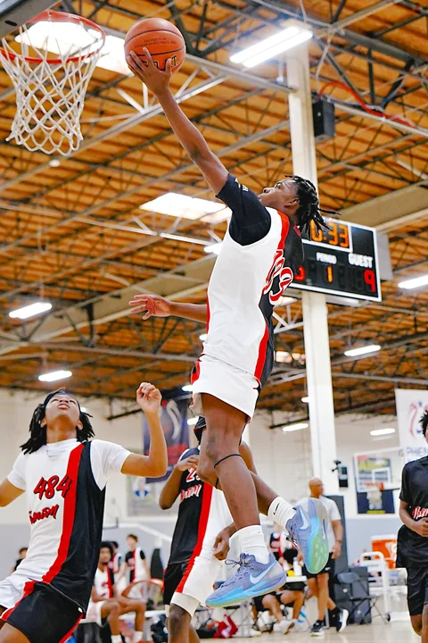 Player in white finishing a layup at the rim